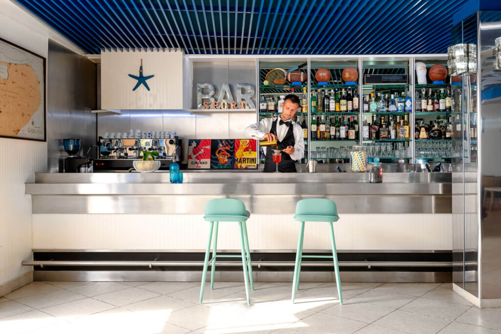 Un barista prepara un drink dietro il bancone di un bar moderno e luminoso.